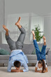 © producer - father copy imitate active child girl doing gymnastic handstand exercise