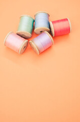 Canvas Print - Colorful sewing threads isolated on a pastel orange background with free space for text