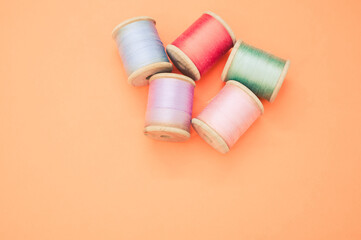 Canvas Print - Colorful sewing threads isolated on a pastel orange background with free space for text