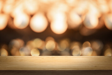 Wall Mural - Gold color bright lights bokeh background of wooden table in front of lights abstract blurred and space use for product