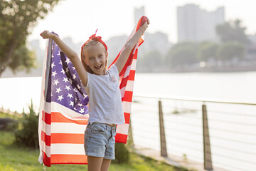 Patriotic holiday. Happy family, mother and daughter with American flag outdoors on sunset. USA celebrate independence day 4th of July.