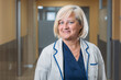 © VICTOR TORRES/Stocksy - Happy real senior medic woman standing in hospital corridor
