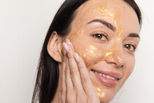 Woman Applying Gold Gel Facial Mask 