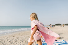 A Little Girl In Pink Towel On The Beach