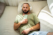 © Eloisa Ramos/Stocksy - modern man sleeping on the sofa with headphones and phone