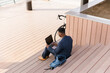 © Mihajlo Ckovric/Stocksy - Young businessman using a laptop outdoors