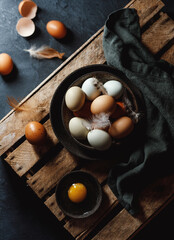 Chicken eggs with feathers in a basket on rustic background. Rustic style