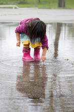 Girl's Reflection In Rain Puddle