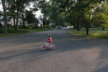 Young Girl Learning To Ride Bike With Training Wheels 