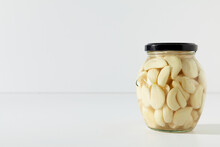 Pickled Garlic In Jar. Glass Jar With Preserved Garlic On White Background With Copy Space.