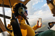 © Marcos Osorio/Stocksy - Helicopter passenger taking photos with his mobile
