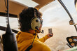 © Marcos Osorio/Stocksy - Helicopter passenger taking photos with his mobile