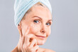 © denis_vermenko - Senior smiling 50s middle aged mature older woman applying facial cream on face looking at camera isolated over white background. Anti age healthy dry skin care beauty therapy concept
