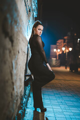 Sticker - Young attractive Caucasian girl leaning on a grunge wall and posing in the evening