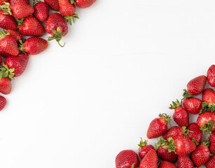 Fresh ripe strawberries placed in the corners on white table with space for text in the center. Top view