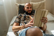 © Eloisa Ramos/Stocksy - modern man relaxing with his tablet at home