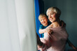 © Olga Moreira/Stocksy - Mother with her little son on her back standing at the window