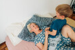 © Olga Moreira/Stocksy - Mother and 5 years old son having fun in bed in the morning