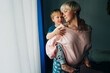 © Olga Moreira/Stocksy - Mother with her little son on her back standing at the window