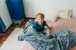 © Olga Moreira/Stocksy - 5 years old blond boy smiling at camera while sitting in bed