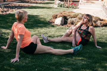 Two active senior women are sitting on grass in the fresh air and doing their favorite hobby. Elderly sports concept