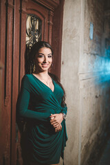 Poster - Young female from Bosnia and Herzegovina in a green elegant dress leaning on the wooden door