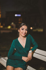 Canvas Print - Young female from Bosnia and Herzegovina in a green elegant dress sitting and posing in the park