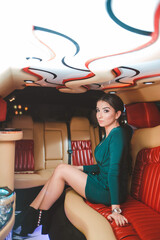 Sticker - Vertical shot of a young elegant female in a green dress posing in a limousine