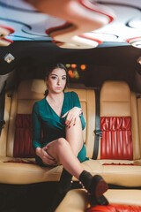 Poster - Portrait of a beautiful sexy Caucasian female wearing an evening cocktail dress sitting in a car