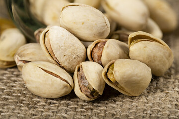 Pistachio nuts arranged on a burlap cloth. A tasty snack consumed with beer.