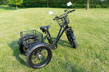 Electric Trike Or Bicycle In The Park In Sunny Summer Day. Unfiltered, With Natural Lighting. E Motor And Power Battery Of The Three Wheel Bike. Ecology And Green Energy Concept. Ev – Electric Vehicle