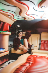 Wall Mural - Vertical shot of a young elegant female in a green dress posing in a limousine