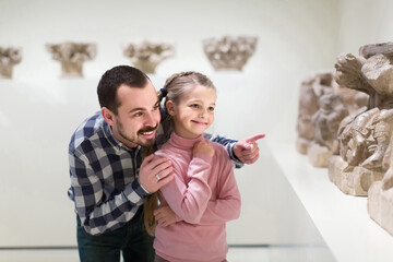 young father and daughter looking at ancient bas-reliefs in museum