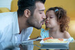 Cute little girl enjoying on the same string of Spaghetti pasta as her father eats, Father's day concept