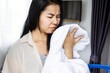 Asian housewife smelling stinky towel, woman having problem with bad smell from clothes