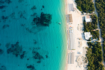 Wall Mural - View from above, stunning aerial view of an empty white sand beach with beach umbrellas and a turquoise, clear water during sunset. Liscia Ruja, Costa Smeralda, Sardinia, Italy.