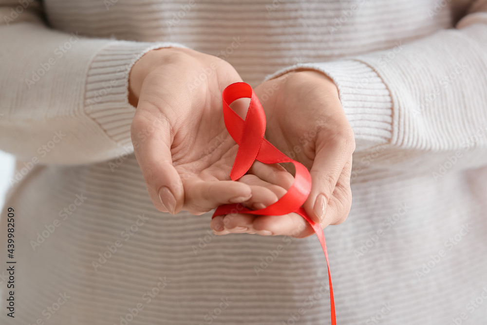 Woman with red ribbon, closeup. Cancer aids awareness concept