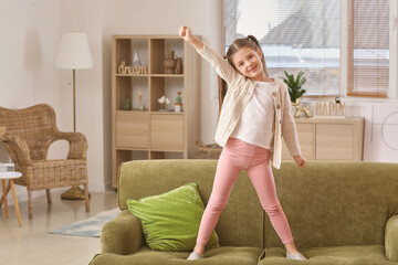 Canvas Print - Happy little girl dancing on sofa at home