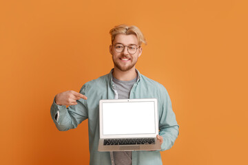 Poster - Handsome man pointing at laptop on color background