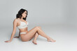 © LIGHTFIELD STUDIOS - Side view of sexy woman in white lace underwear sitting on grey background