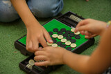 Fototapeta  - Closeup of kids hands playing reversi or othello traditional strategic board game by thinking, planing and use fingers flip the black reversible disc. Cognitive skills, Mind sport, Competitive concept