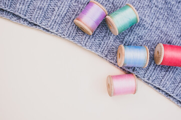 Sticker - Colorful sewing threads with grey fabric on a light background with free space for text