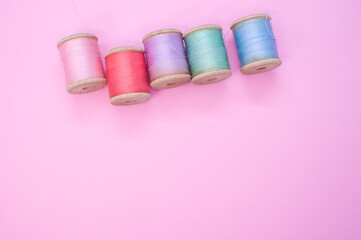 Wall Mural - Colorful sewing threads isolated on a pink background with free space for text