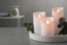Decorative LED Candles And Eucalyptus On Grey Table, Space For Text