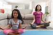 © Wavebreak Media - Smiling hispanic mother and daughter meditating in living room