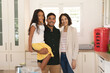 © Wavebreak Media - Portrait of happy hispanic daughter and parents standing in kitchen smiling