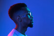 © master1305 - African-american young man's portrait on dark studio background in neon. Concept of human emotions, facial expression, youth, sales, ad.