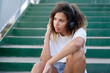 © gpointstudio - Close up of girl with headphones sitting on the stairs