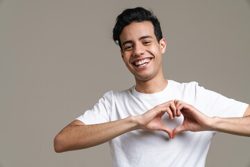 brunette hispanic man in t-shirt smiling and showing heart gesture