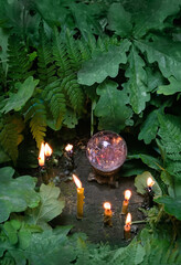 Wall Mural - Burning candles and quartz crystal ball, fern and oak leaves, natural forest background. crystal ball for meditation, relaxation, Witchcraft. healing mineral. wicca spiritual practice